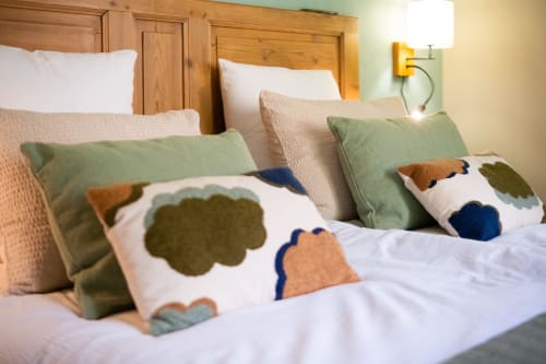 Chambre cosy du Jardin Secret à Grignan avec tête de lit en bois, coussins colorés et literie blanche