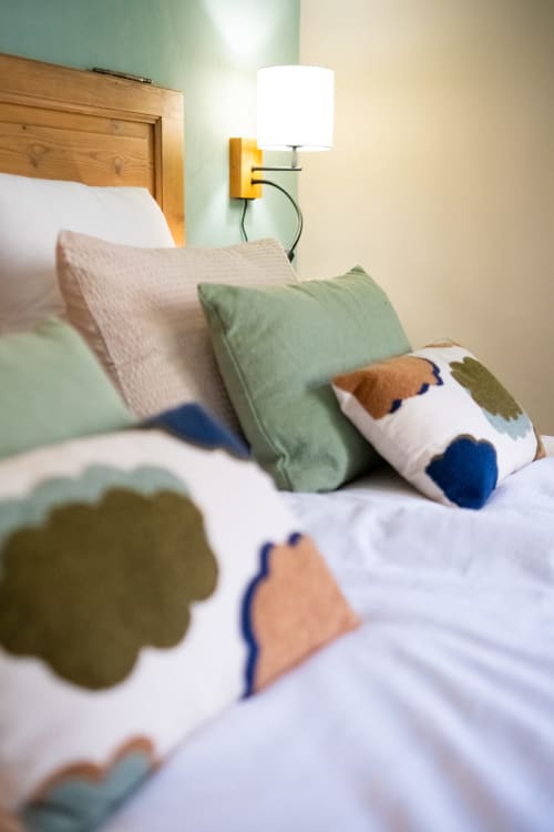 Chambre cosy au Jardin Secret à Grignan avec coussins décoreratifs et lampe murale jaune