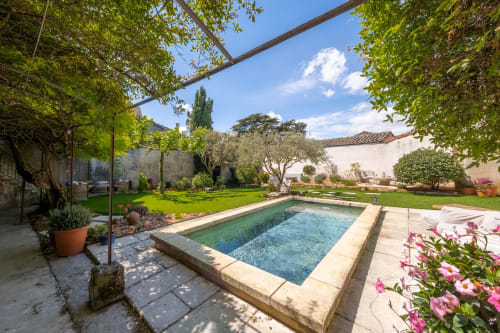 La cour piscine du Jardin Secret à Grignan avec jardins luxuriants, plantes fleuries et pergola ombragée