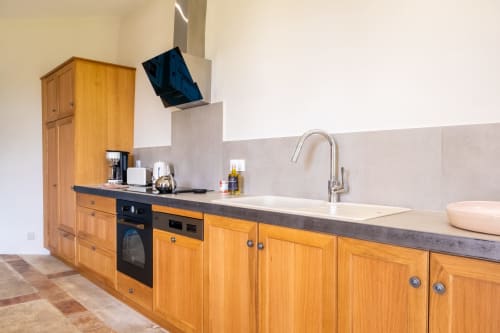 Cuisine moderne de l'Appartement la Glycine au Jardin Secret, Grignan avec meubles en bois et plan de travail gris