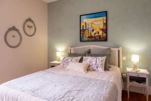 Chambre accueillante au Jardin Secret à Grignan avec lit queen-size, oreillers fleuris et tableaux encadrés au-dessus de la tête de lit