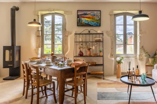 Spacieuse salle à manger et salon du Jardin Secret à Grignan avec table en bois, cheminée et fenêtres panoramiques