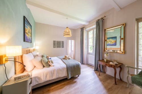 Chambre lumineuse au Le Jardin Secret B&B à Grignan avec lit queen-size, mobilier en bois, luminaires suspendus et vue sur le jardin