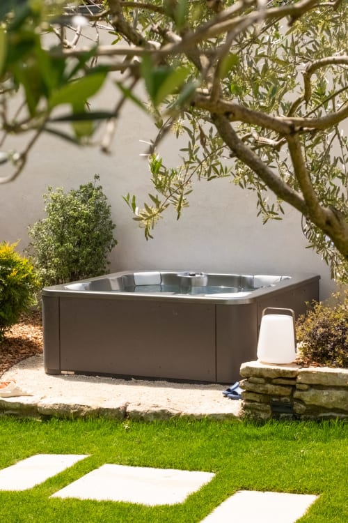 Luxueux bain à remous dans un jardin serein du Jardin Secret à Grignan, entouré d'oliviers et de paysages aménagés