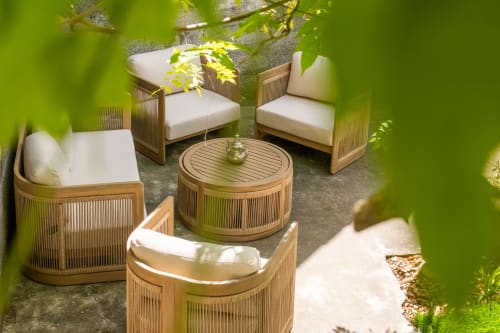Mobilier de patio en bois avec coussins crème disposés autour d'une table ronde au Jardin Secret, Grignan