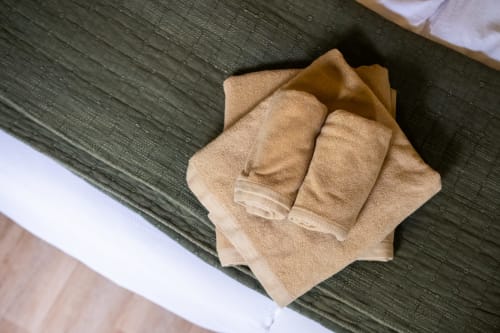 Serviettes beige soigneusement pliées sur sol en bois foncé, Suite le Jasmin au Jardin Secret, Grignan