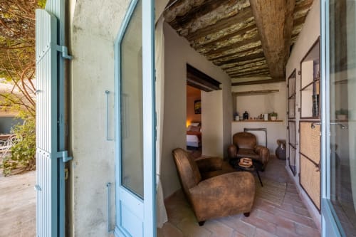 La Suite Le Jasmin du Jardin Secret à Grignan avec ses poutres apparentes, fauteuils en cuir et carrelage en terre cuite