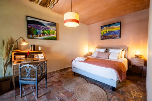 Chambre Suite le Jasmin au Jardin Secret B&B à Grignan, France avec mobilier en bois, éclairage chaleureux et vue sur la piscine