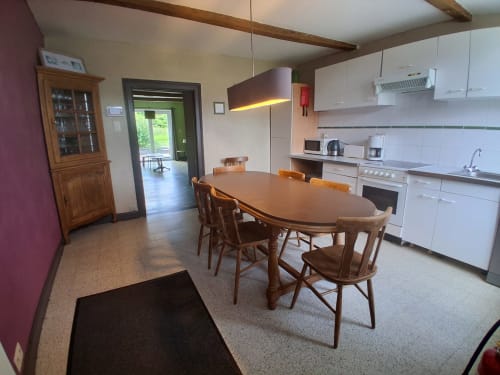 Cuisine et salle à manger modernes des Trois Voisins B&B à Bourseigne-Vieille avec table en bois, chaises et mobilier blanc