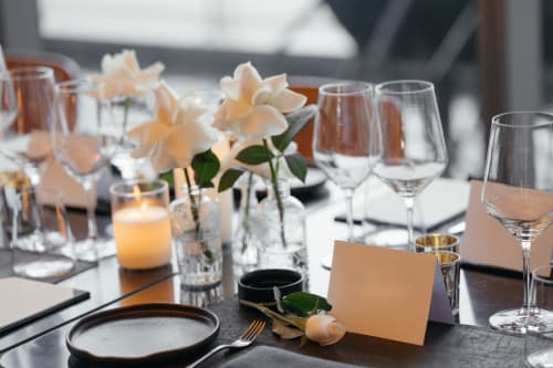 Mise en place élégante au Domaine des Oiseaux de Passage avec roses pêche, marque-places et verres à vin