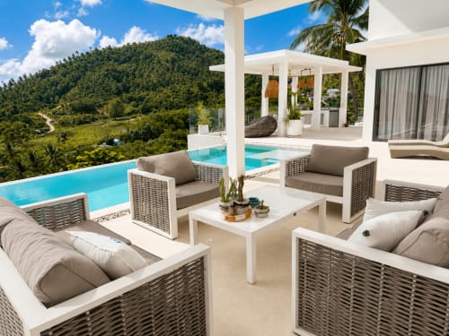 Villa de luxe à Ko Samui avec piscine à débordement, mobilier en rotin, vue sur la jungle et pergola blanche moderne.