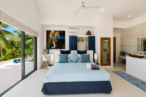 Grande chambre principale de l'Indigo Villa Samui avec vue mer, literie bleu clair, accents bleu marine et salle de bains attenante