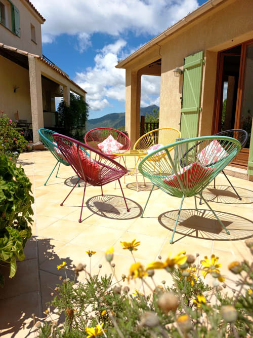 Chaises colorées tissées sur la terrasse ensoleillée de la Mare e Monti Vico avec vue sur les montagnes