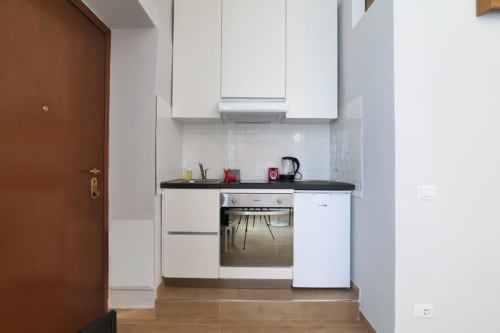 Cucina bianca moderna con piano cottura nero e elettrodomestici nell'appartamento Navigli, Milano