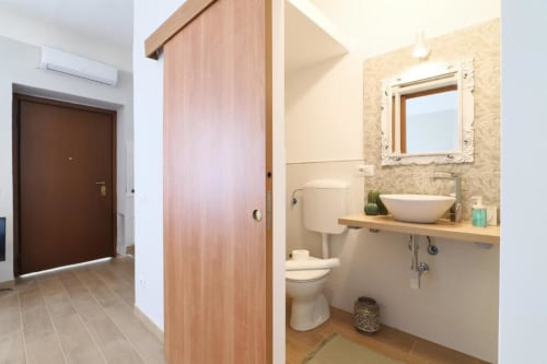 Bagno moderno dell'appartamento ACasaDiImma a Milano con lavabo a vessel, porta scorrevole in legno e finiture contemporanee