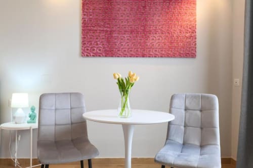 Zona living moderna dell'appartamento ACasaDiImma Milano con tavolo tondo bianco, sedie trapuntate grigie, tulipani gialli e rosa