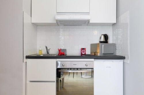 Cucina moderna con piano di lavoro nero, mobili bianchi e elettrodomestici in acciaio inox nell'appartamento di Milano