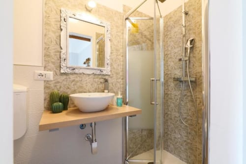 Bagno moderno presso ACasaDiImma Milano con lavabo a bacinella, vanità in legno e doccia con box in vetro