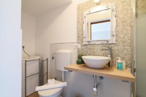 Bagno moderno dell'appartamento ACasaDiImma Milano con lavabo bianco, specchio decorativo, scaldasalviette e vista sul giardino