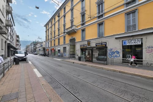 Strada del quartiere Navigli a Milano con edificio giallo, binari del tram e vetrine per l'appartamento ACasaDiImma