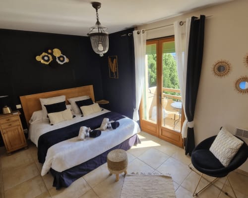 Chambre Bavella au Mare e Monti à Vico : vue montagne, lit en bois, mur d'accent bleu marine, balcon et salon