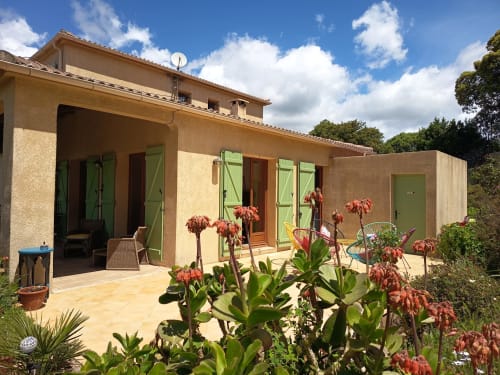 Gîte Mare e Monti à Vico avec volets verts, terrasse, fleurs rouges et vue sur les montagnes