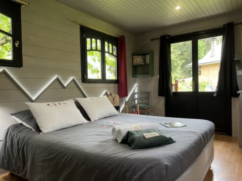 Bright bedroom at La Jument Verte B&B in Trévignin with mountain-view windows, gray bedding, and modern white headboard