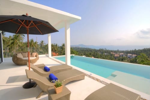 Villa de luxe à Ko Samui avec piscine à débordement, transats, parasol et vue tropicale sur mer