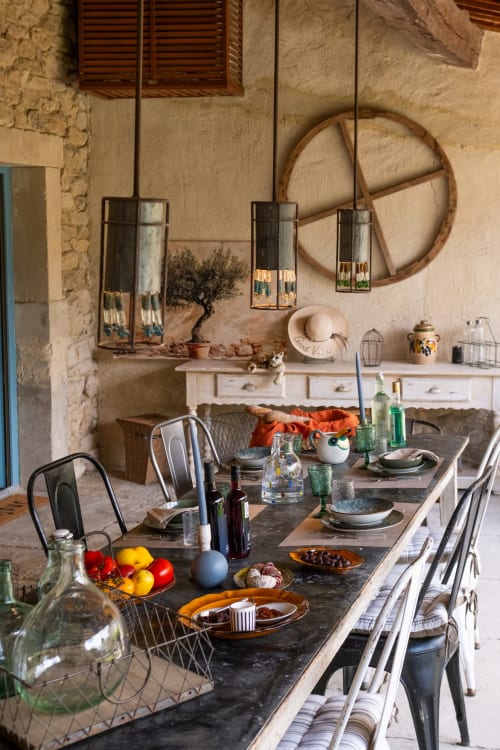 Salle à manger rustique du gîte Le Jardin Secret à Grignan avec murs en pierre, grande table dressée et décoration vintage