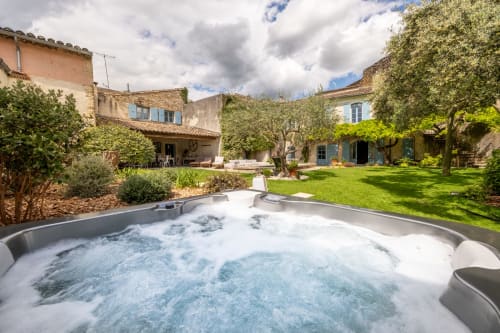 Baignoire à bulles frémissante dans la cour du gîte Le Jardin Secret à Grignan, entourée de bâtisses en pierre recouvertes de lierre