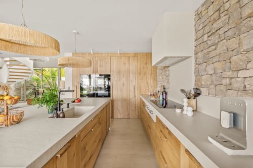 Cuisine moderne de villa avec meubles en bois, mur en pierre et vue sur mer à Jc Conciergerie, Bandol