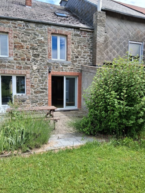 Cour de pierre des Trois Voisins avec patio et verdure abondante à Bourseigne-Vieille