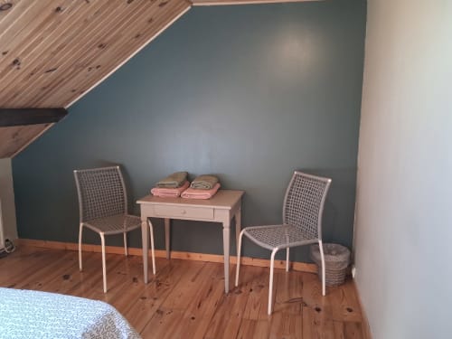 Coin chambre douillet aux Trois Voisins avec bureau rose, deux chaises et parquet sous plafond mansardé