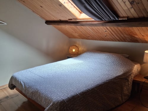 Chambre mansardée douillette aux Trois Voisins avec poutres apparentes et éclairage chaleureux