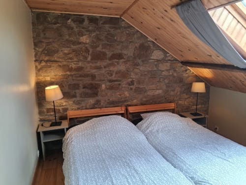 Chambre cosy mansardée aux Trois Voisins B&B à Bourseigne-Vieille avec murs en pierre, poutres bois et lits jumeaux.