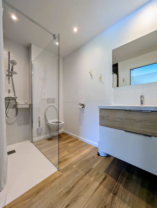 Salle de bain moderne avec douche à l'italienne, vasque blanche et parquet à La Clairière aux Chênes
