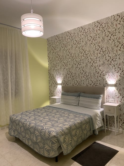 Modern bedroom at Ca' Popolo Venice BnB with patterned wallpaper, pendant light, striped bedding, and bedside lamps