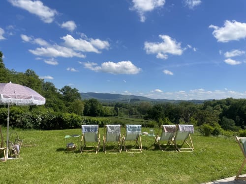 Deck chairs on green lawn overlooking Morvan landscape at Château de Vaux, Étang sur Arroux, France