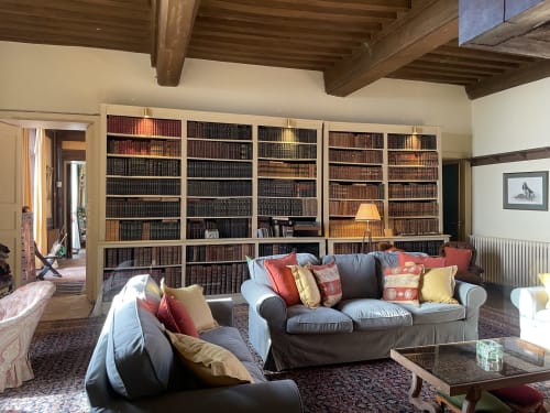 Elegant library lounge at Château de Vaux Morvan with floor-to-ceiling bookshelves, gray sofas, and wooden beams