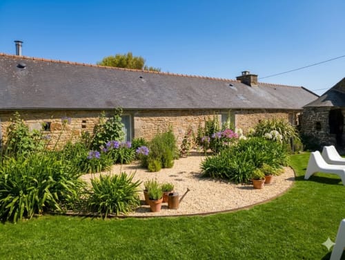 Cottage en pierre Espace Ker Gana avec jardins soignés et fleurs violettes à Plourin, France