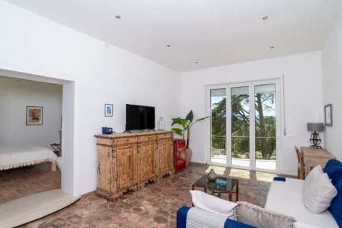 Camera Deluxe al Domo Cadò B&B di Berchidda con zona living, divano, cassettone in legno, TV e porte in vetro
