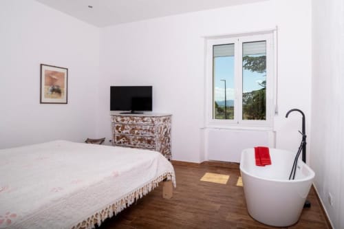 Camera da letto deluxe a Domo Cadò a Berchidda con letto, TV, vasca indipendente e vista giardino da ampie finestre