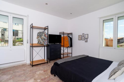 Spaziosa camera doppia al Domo Cadò di Berchidda con arredamenti moderni, TV schermo piatto, letto nero e vista dal balcone