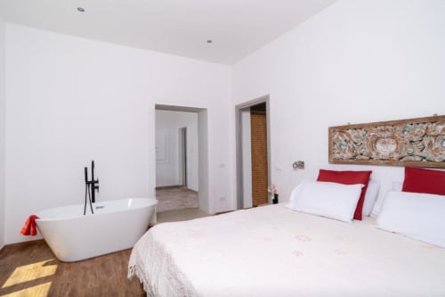 Camera deluxe Domo Cadò con vasca indipendente, letto king con cuscini rossi, pavimenti in legno e vista giardino a Berchidda