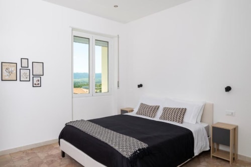 Spaziosa camera doppia a Domo Cadò a Berchidda con vista panoramica sulla valle, arredamento moderno e decoro bianco e nero