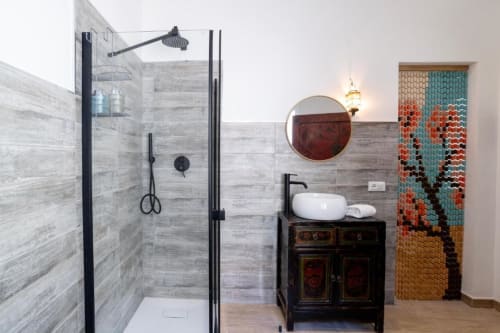 Bagno moderno a Domo Cadò con doccia in piastrelle grigie, specchio rotondo, lavabo a coppa e tenda decorativa in perline