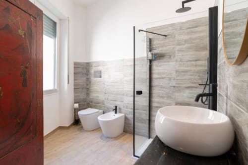 Bagno moderno a Domo Cadò a Berchidda con vasca ovale bianca, WC, bidet e doccia a pioggia con rubinetteria nera