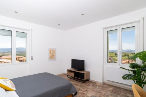 Luminosa camera doppia superior presso Domo Cadò con vista sul giardino, comfort moderni e paesaggio della campagna berchiddese
