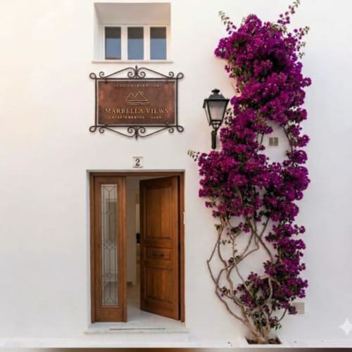 Entrada de Marbella Views en Ojén con puerta de madera número 2 y buganvilla magenta trepando por la pared blanca