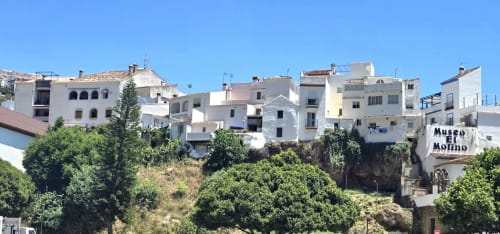 Edificios encalados de pueblo blanco en ladera de Ojén cerca de Marbella, España, con señal de Museo del Molino visible